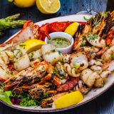 Seafood platter. Grilled lobster, shrimps, scallops, langoustines, octopus, squid on white plate.
